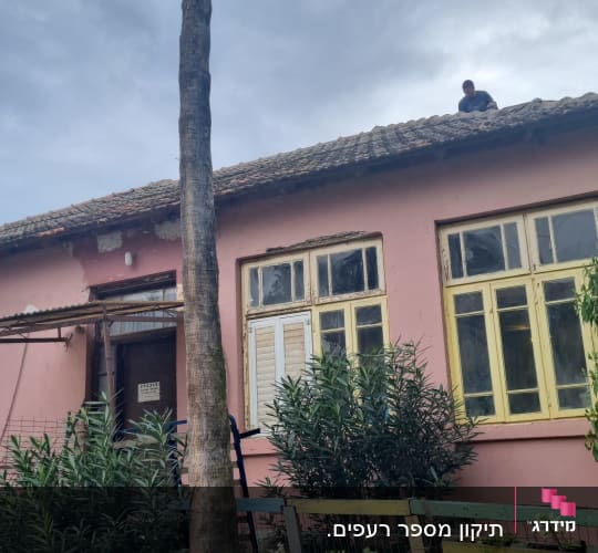 אדם עומד על גג רעפים של בית ורוד.